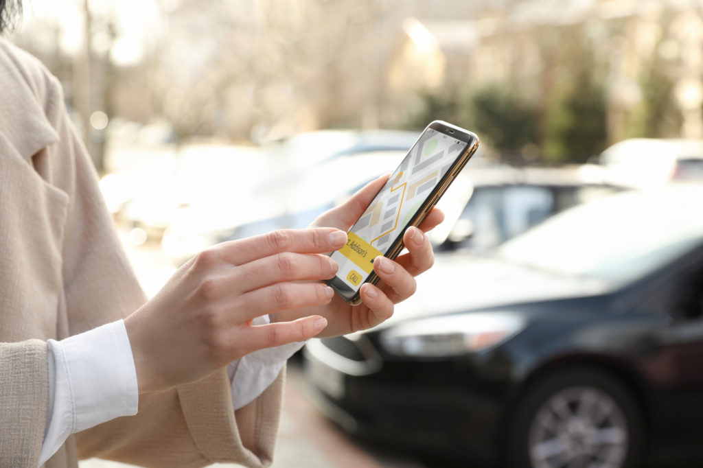 Uber Accident Lawyer Anaheim, CA - Woman ordering taxi with smartphone on city street, closeup