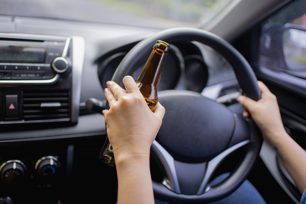 Driver holding a beer bottle while gripping the steering wheel in Los Angeles