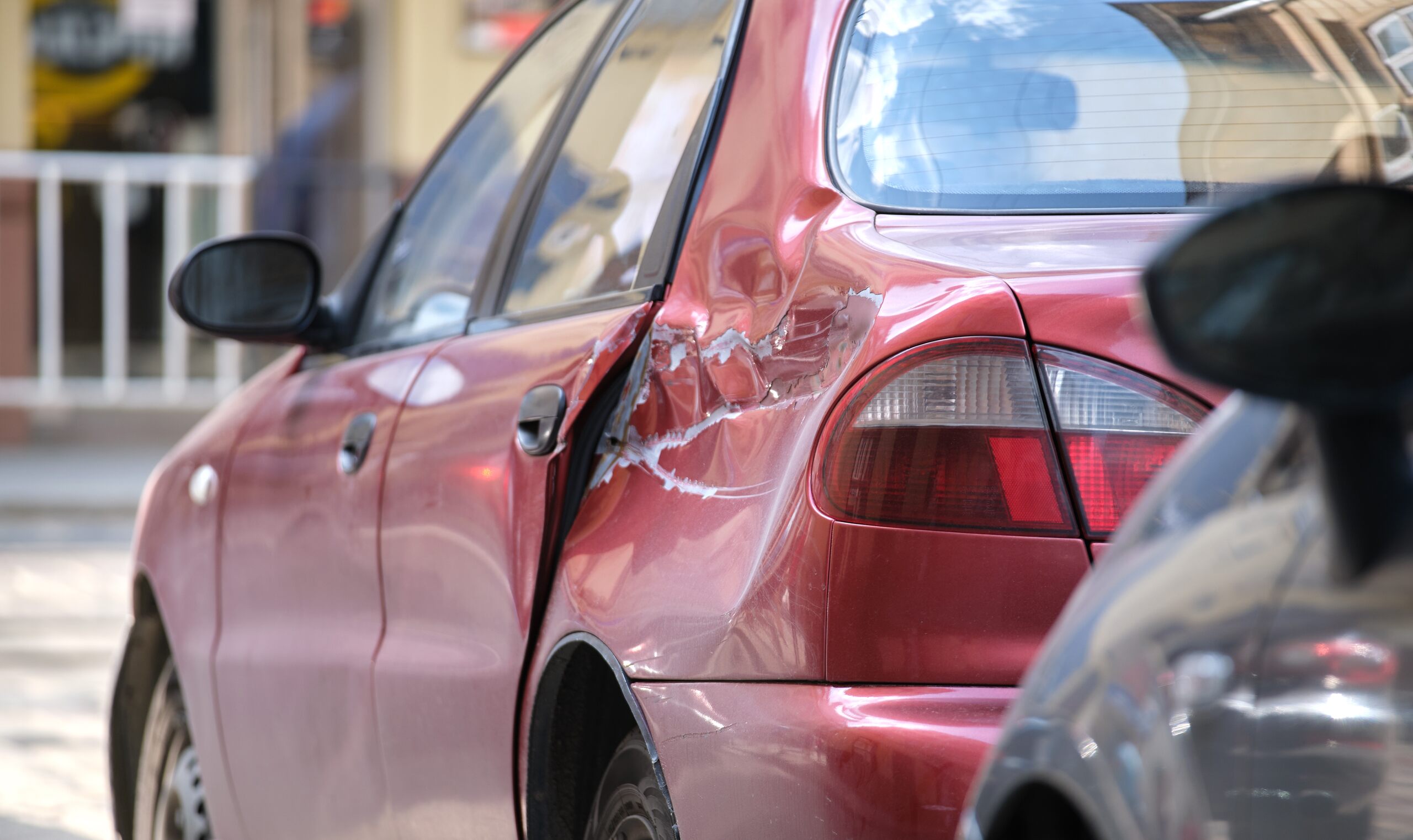 A red car shows severe side door damage evaluated by Burbank car accident lawyers.