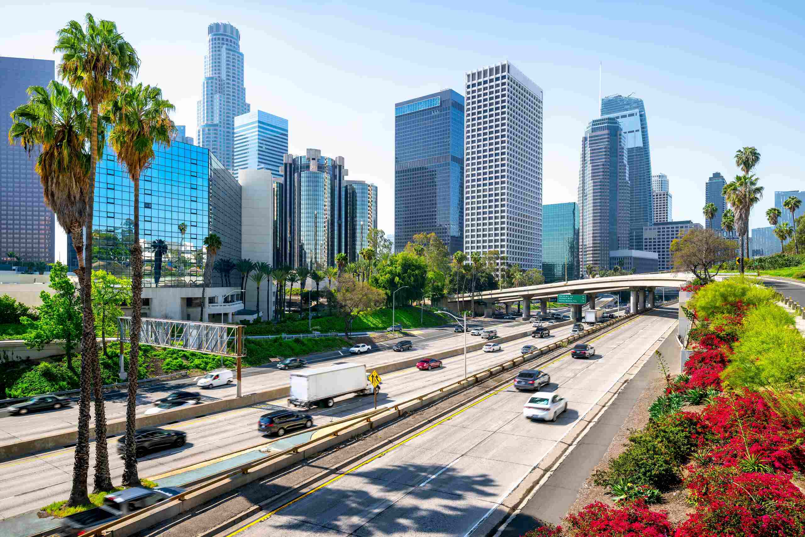 Heavy traffic moves on a freeway near downtown skyscrapers represented by Los Angeles hit and run attorneys.