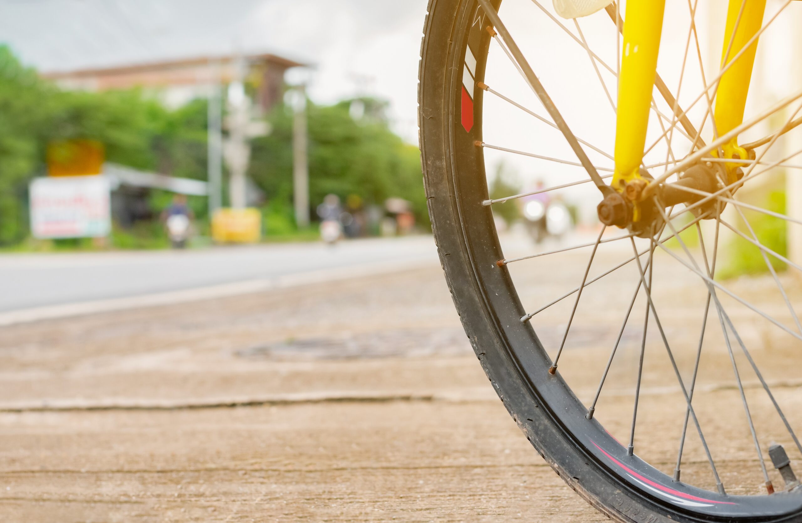 Close-up of a bicycle front wheel on a paved roadside.