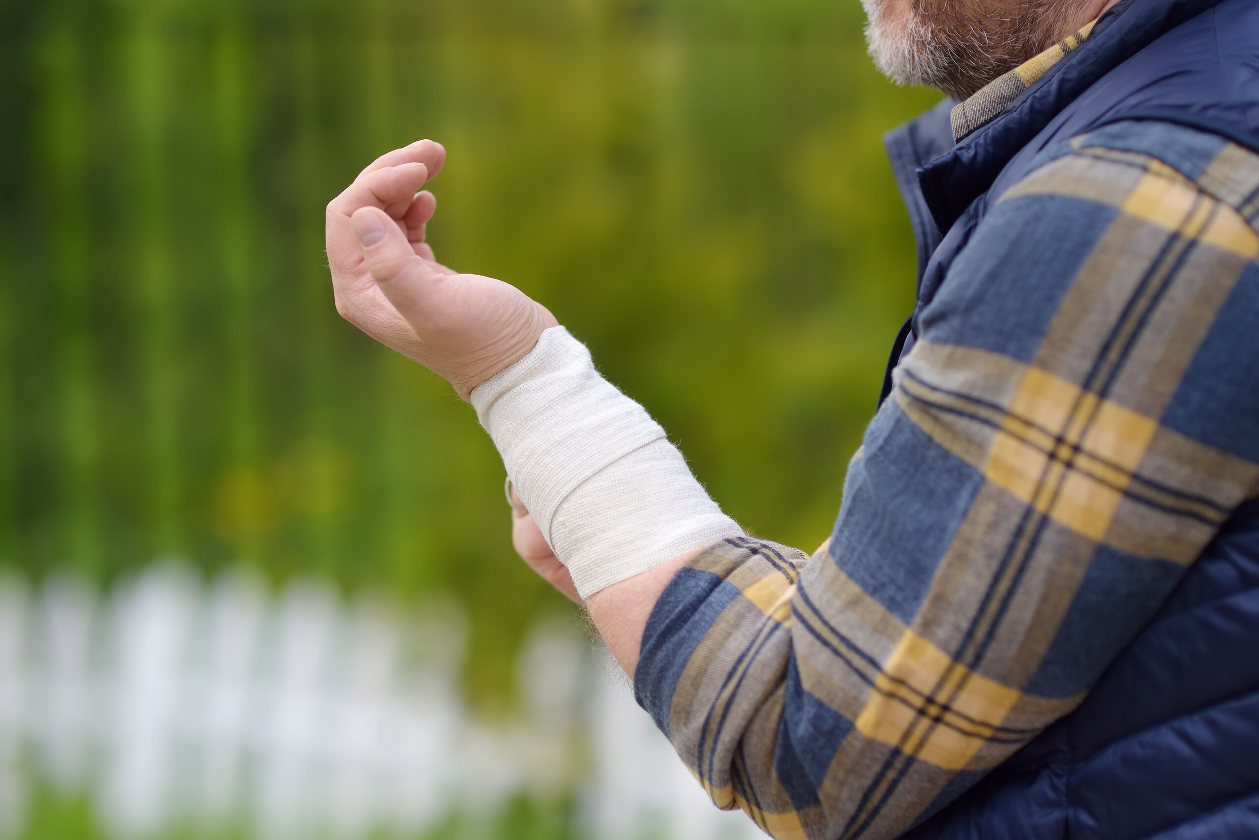 A person wearing a plaid shirt and vest with a white medical bandage on their wrist, seeking help from an Anaheim personal injury attorney.