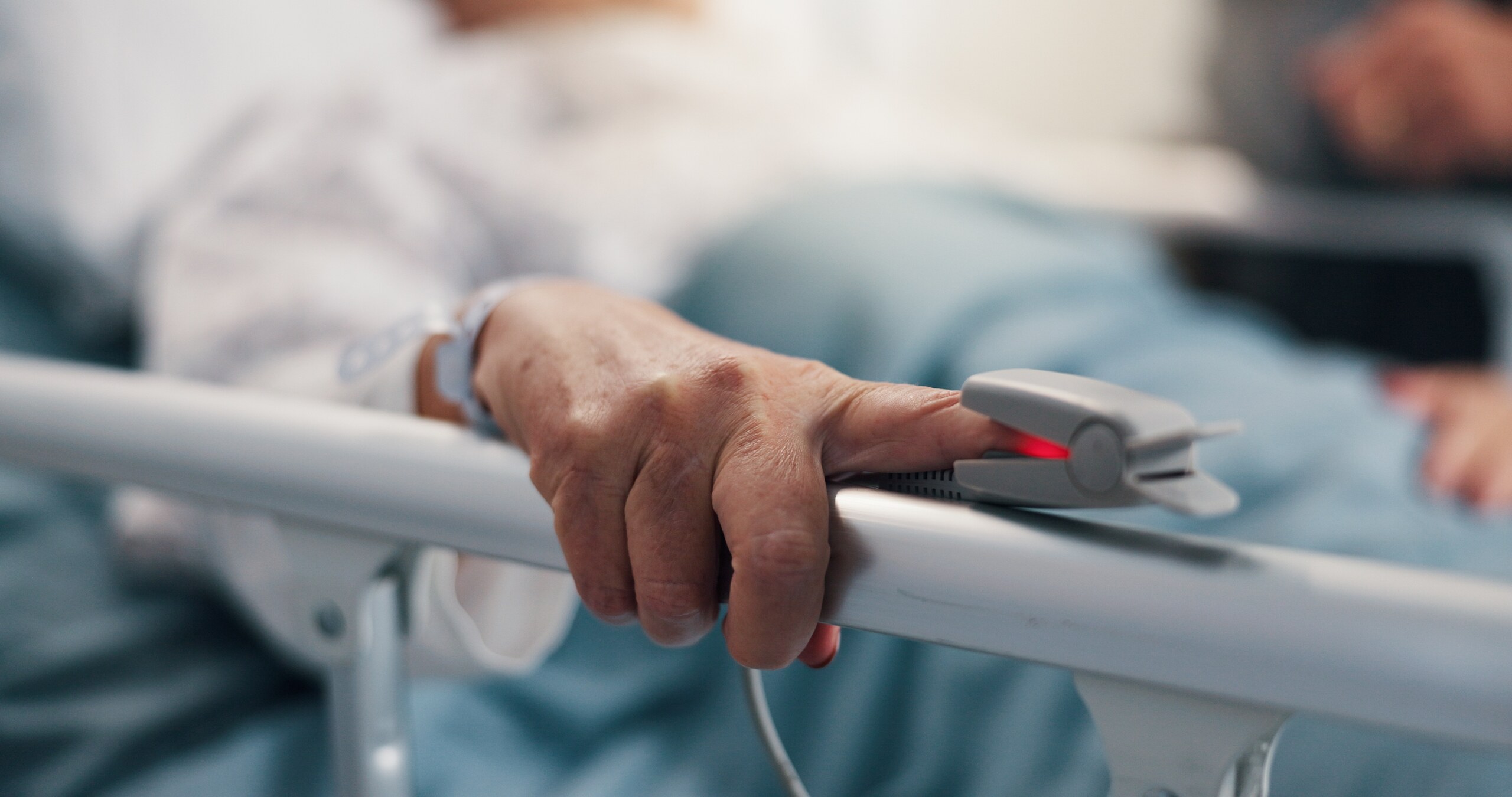 A patient’s hand with a pulse oximeter on the index finger resting on a hospital bed rail, documenting injuries relevant to an Anaheim personal injury attorney.