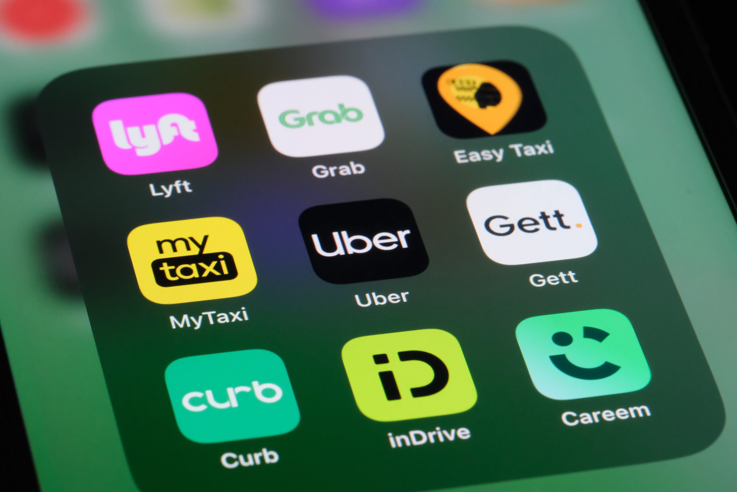 A smartphone screen displaying a grid of various ride-sharing app icons, including Lyft, Grab, Easy Taxi, MyTaxi, Uber, Gett, Curb, inDrive, and Careem.